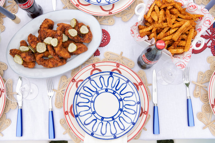Large white oval ceramic platter with fried chicken pieces and dollops of sauce on a white tabletop setting.