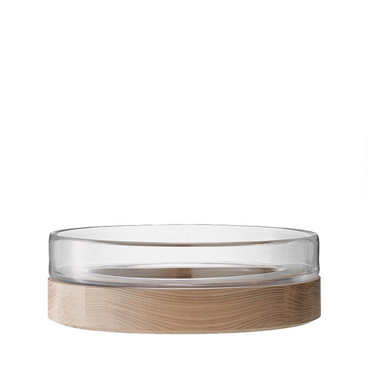 Clear glass serving bowl with wide rim on a light wood base.