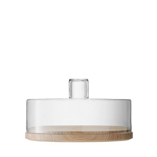 Clear glass dome with cylindrical handle on round light wood base for serving cakes or charcuterie.