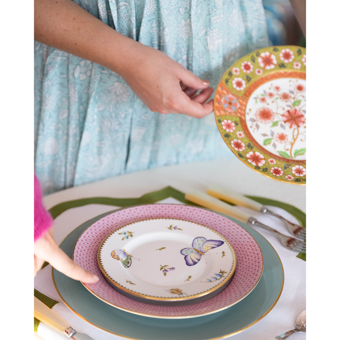 Round bread and butter plate with butterfly and floral meadow design on white background.