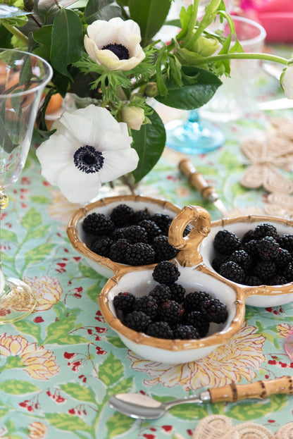 Triple bamboo cocktail server with three natural curved bowls filled with blackberries on a floral tablecloth.