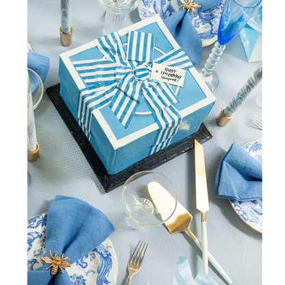 Gold bee-shaped napkin ring holding a blue linen napkin on a white and blue floral plate.