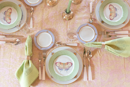 Green apple cocktail plate with lace edge and butterfly accent in a set table arrangement.