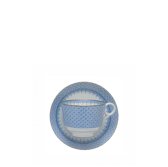 Cornflower blue lace-patterned ceramic cup with matching saucer on white background.
