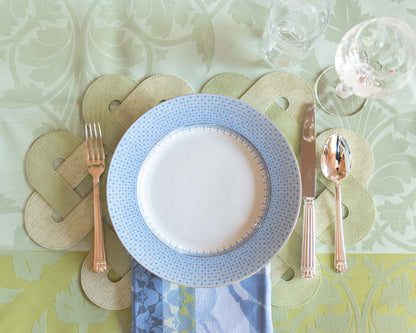 Dinner plate with delicate cornflower blue lace pattern rim on white center, set on a quilted beige placemat.