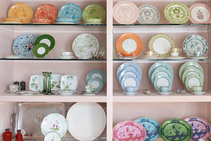 Green apple lace dinner plate with intricate embossed pattern on wooden shelf.