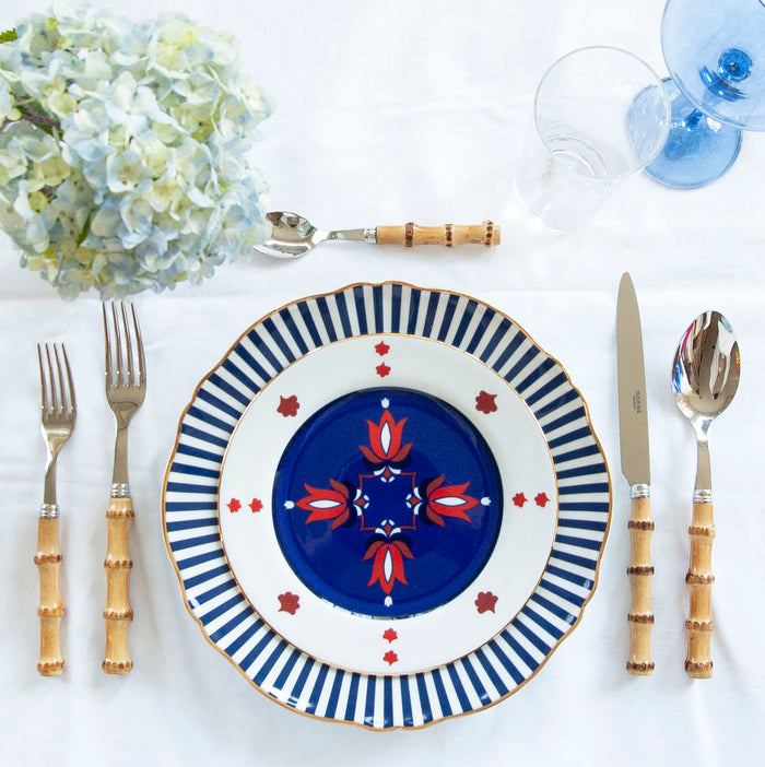 Blue ceramic dinner plate with geometric floral pattern and bamboo-style handle flatware set.