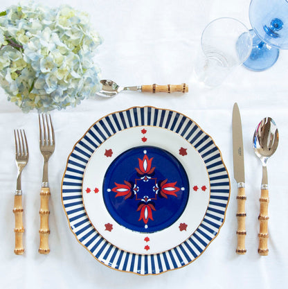 Blue ceramic dinner plate with geometric floral pattern and bamboo-style handle flatware set.