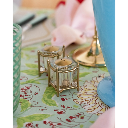 Gold-toned New York Diner salt and pepper shakers with clear glass panels on floral tablecloth.