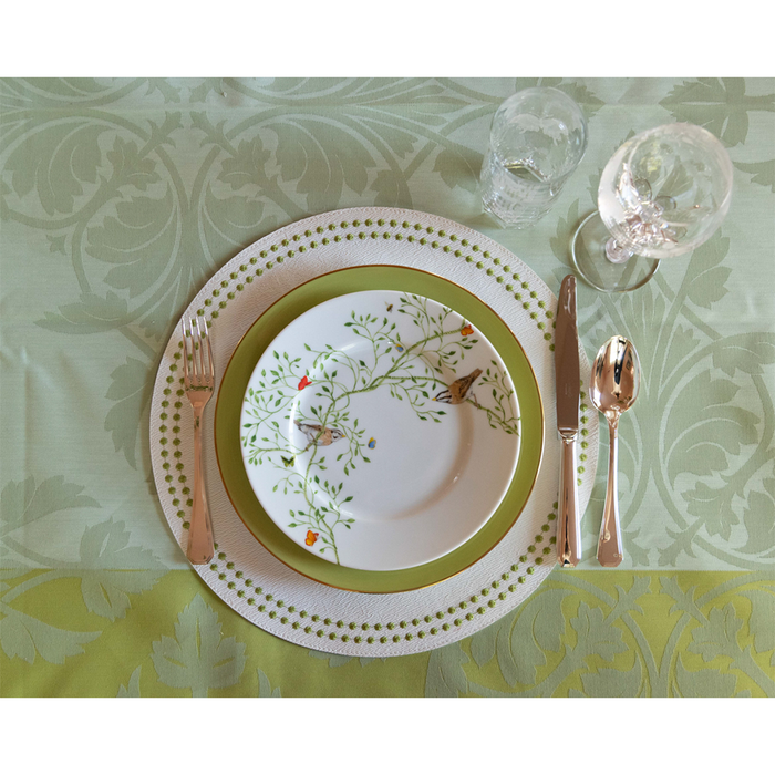Chartreuse Olivia Dot placemat with white and green patterned plate, gold flatware, and glassware on floral tablecloth.