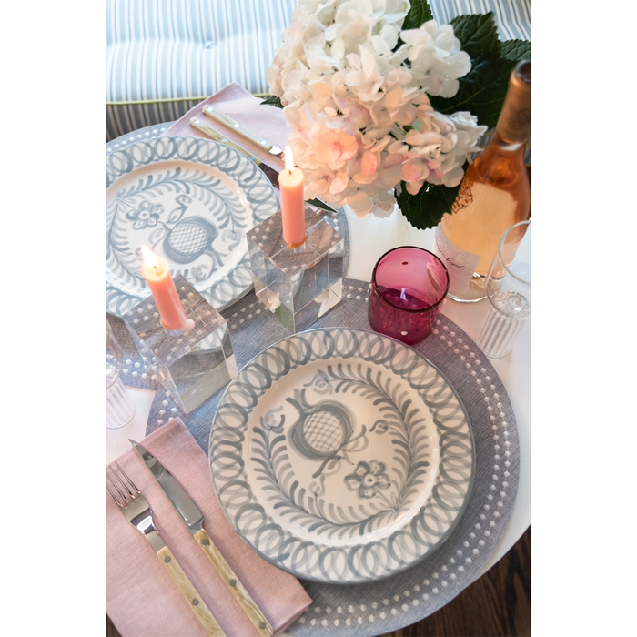 Gray Olivia Dot placemat under blue and white patterned plates with pink napkin and candles.