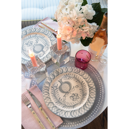 Gray Olivia Dot placemat under blue and white patterned plates with pink napkin and candles.