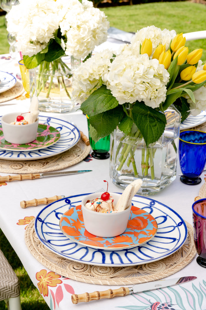Whitewash ceramic ramekin with smooth matte finish on a patterned blue and white plate with flowers and woven placemat.