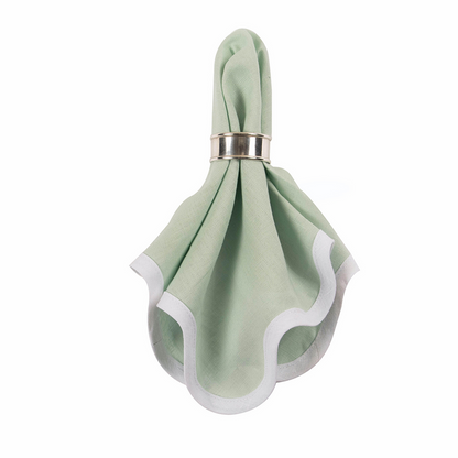 Sage green linen napkin with white scalloped edges held in a silver napkin ring.