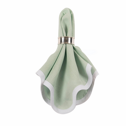 Sage green linen napkin with white scalloped edges held in a silver napkin ring.
