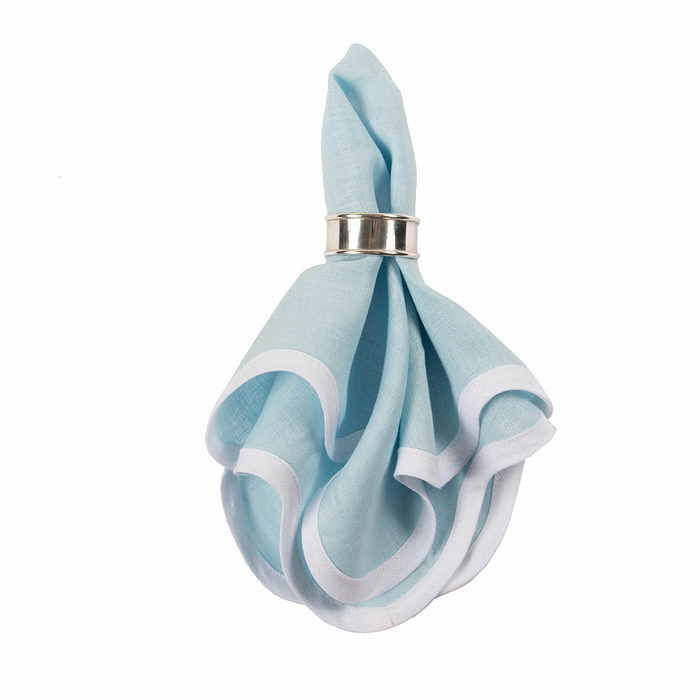 Sky blue linen napkin with white scalloped edges folded in silver napkin ring.