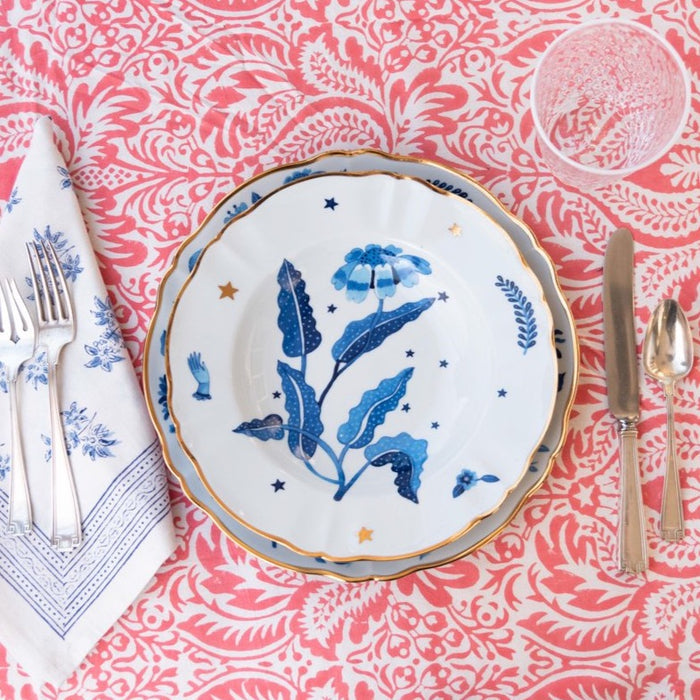 Blue ceramic deep plate with hand-painted botanical design, gold rim, and scattered star accents.