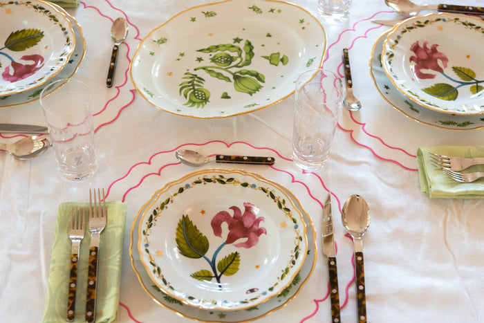Oval green ceramic serving platter with painted leaf and star patterns on a white tablecloth.