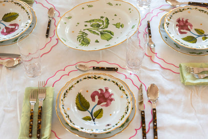 Oval green ceramic serving platter with painted leaf and star patterns on a white tablecloth.