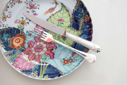 Round dinner plate with colorful floral and peacock feather patterns and scalloped edge.